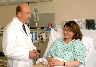 一个穿着青绿色擦洗服的女人坐在一个穿着白色医用擦洗服的男人旁边